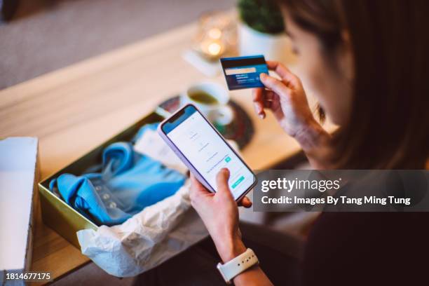 young beautiful asian woman shopping online with smartphone & paying with credit card at home. - e-commerce stock-fotos und bilder