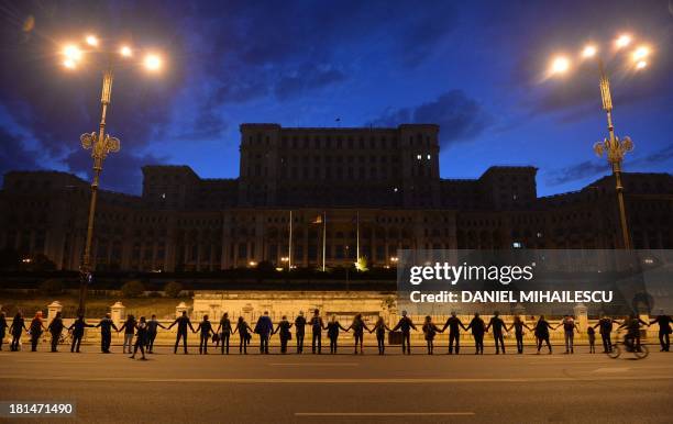 People stand together to form a human chain around the Romanian Parliament building in a protest against the Rosia Montana Gold Corporation , a...