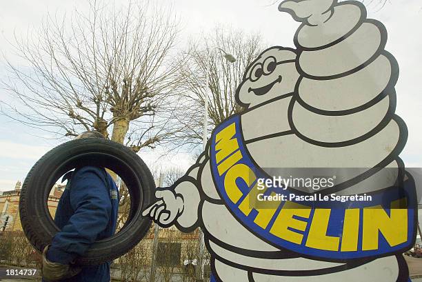 Worker holds a Michelin tire near the Michelin Man logo February 25, 2003 in Saint Germain en Laye outside of Paris. The French tire maker announced...