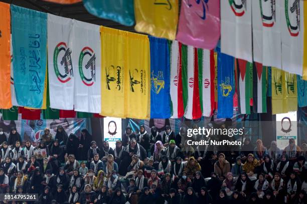 Female members of the Basij paramilitary forces are sitting beneath the flags of Lebanon's Hezbollah, the Islamic Revolutionary Guard Corps , Iran,...