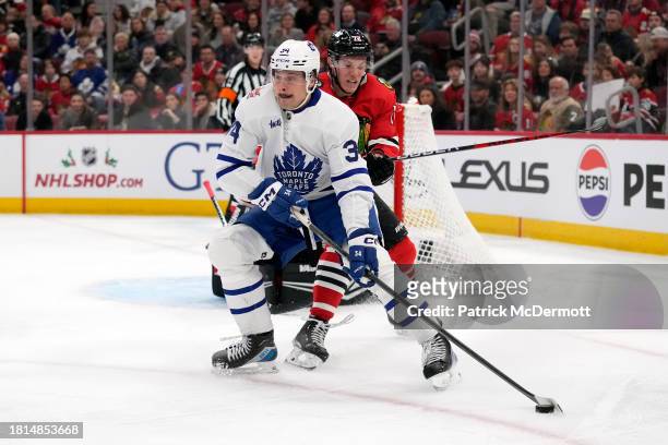 Auston Matthews of the Toronto Maple Leafs skates with the puck against Alex Vlasic of the Chicago Blackhawks during the third period at the United...