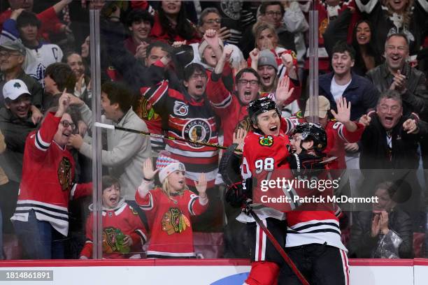 Kevin Korchinski of the Chicago Blackhawks celebrates with teammate Connor Bedard after scoring the game winning goal against the Toronto Maple Leafs...