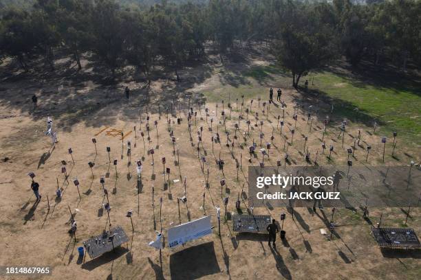 In this aerial view, Israeli soldiers walk among the pictures of people taken captive or killed by Hamas militants duing the Supernova music festival...