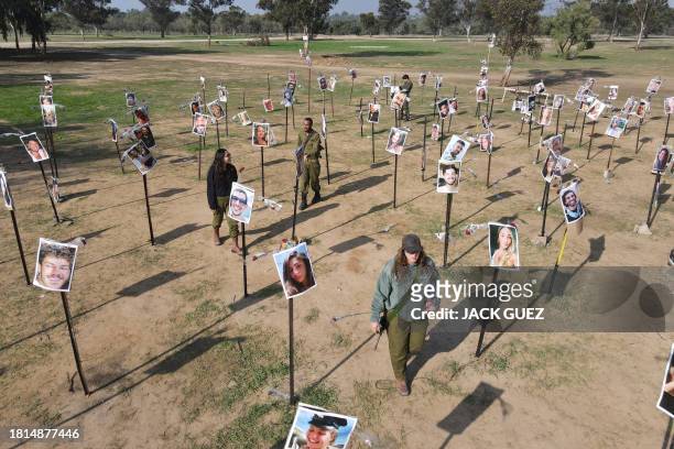 Israeli soldiers walk among the pictures of people taken captive or killed by Hamas militants duing the Supernova music festival on October 7, at the...