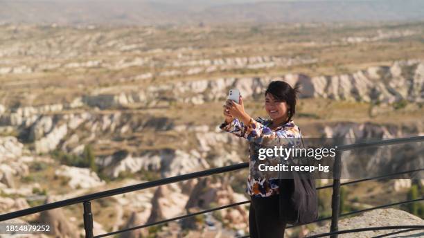 multiracial beautiful female tourist using her smart mobile phone to take photos and videos in cappadocia in türkiye turkey - göreme national park stock pictures, royalty-free photos & images