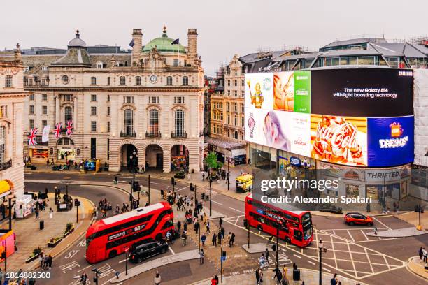 illuminated piccadilly circus with red double-decker buses and advertising screens, london, england, uk - piccadilly stock-fotos und bilder