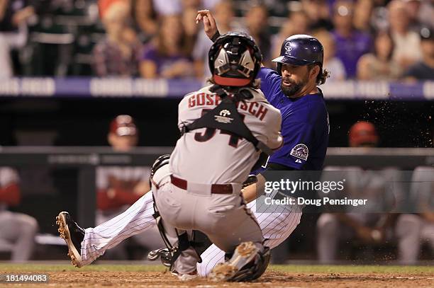 Todd Helton of the Colorado Rockies slides home past catcher Tuffy Gosewisch of the Arizona Diamondbacks to score on a sacrifice fly by Jordan...