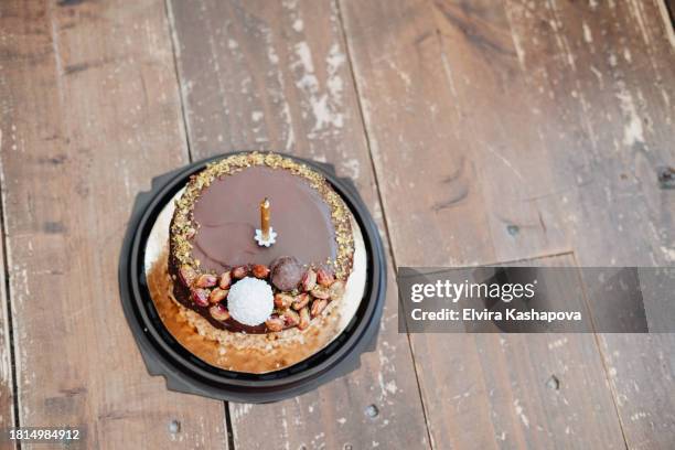 small chocolate bento cake with 1 golden candle on wooden parquet floor, top view - 1 year anniversary stock pictures, royalty-free photos & images