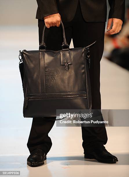 Model shows details of handbag collection as he walks the runway at Versace Collection show during Ciputra World Fashion Week 2013 on September 21,...