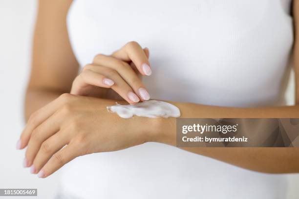 woman putting white cream on hand - putting sunscreen stock pictures, royalty-free photos & images