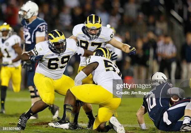 Willie Henry, Frank Clark and Brennen Beyer of the Michigan Wolverines celebrate after sacking Chandler Whitmer of the Connecticut Huskies in the...