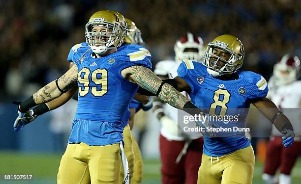 Defensive end Cassius Marsh of the UCLA Bruins celebrates with linebacker Deon Hollins after Marsh tackled quarterback King Davis III of the New...