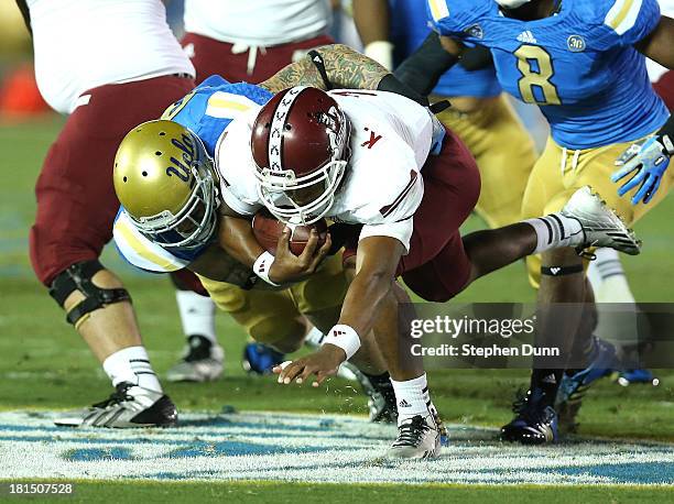 Defensive end Cassius Marsh of the UCLA Bruins tackles quarterback King Davis III of the New Mexico State Aggies for a loss at the Rose Bowl on...