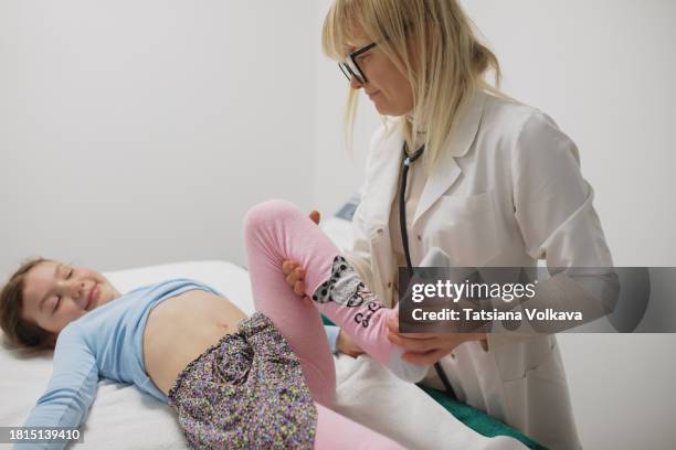 a young girl, under the care of her female pediatrician, undergoes a thorough examination. the physician attentively assesses the girl's abdomen, employing gentle palpation to detect any potential signs of discomfort. - pediatra donna foto e immagini stock