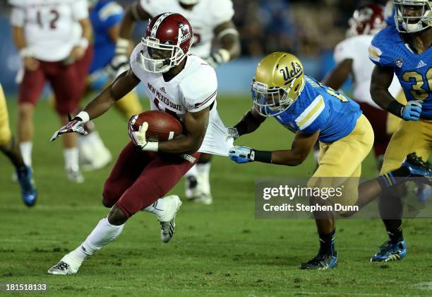 Wide receiver Jerrel Brown of the New Mexico State Aggies carries the ball as cornerback Charles Dawson of the UCLA Bruins pulls his jersey at the...