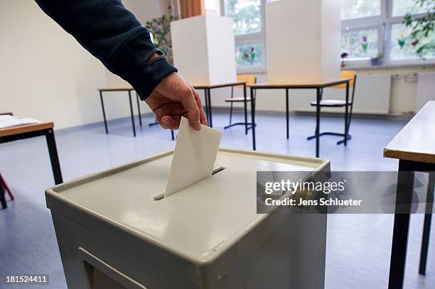 Voter puts his ballot in a ballot box at a primary school on September 22, 2013 in Halle, Germany. Germany is holding federal elections that will...