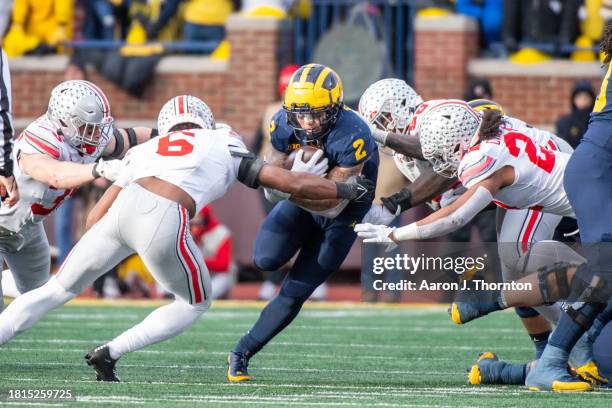 Blake Corum of the Michigan Wolverines runs with the ball for yardage against Sonny Styles and Steele Chambers of the Ohio State Buckeyes during the...