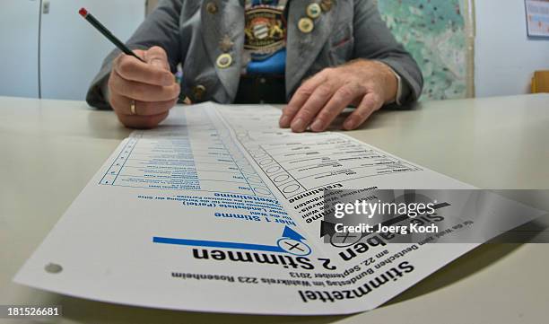 Man in a traditional Bavarian dress fills out his card in a voting booth before he casts his vote in the federal elections at the "Schoenau...