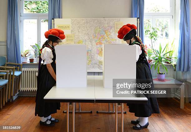 Voters Gerlinde Moser and Corinna Wöhrle wear a Black Forest traditional clothes and the pom-poms hat "Bollenhut" as they cast their ballot at a...