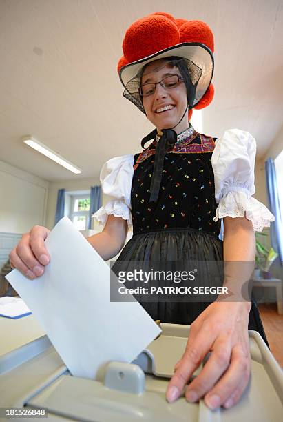 Voter Gerlinde Moser wears Black Forest traditional clothes and the pom-poms hat "Bollenhut" as she casts her ballot at a polling station on...