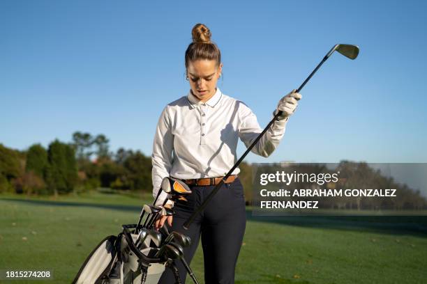 young woman putting the golf club in the bag - golfer stock pictures, royalty-free photos & images