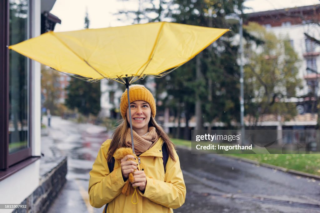 Funny portrait of a teenage girl with umbrella flipped inside out by the wind