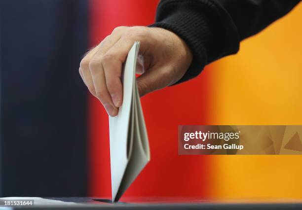 Voter casts his ballot in German federal elections as a German flag hangs behind on September 22, 2013 in Berlin, Germany. Germany is holding federal...