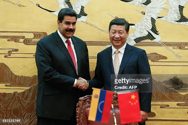 Chinese President Xi Jinping and Venezuela's President Nicolas Maduro shake hands during a signing ceremony between the two countries at the Great...