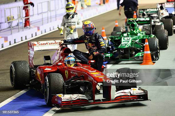 Mark Webber of Australia and Infiniti Red Bull racing is given a lift back to pits by Fernando Alonso of Spain and Ferrari after his engine blew up...