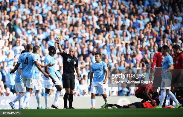 Referee Howard Webb shows a yellow card to Matija Nastasic of Manchester City during the Barclays Premier League match between Manchester City and...