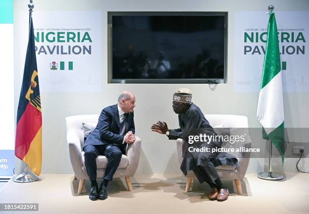 December 2023, United Arab Emirates, Dubai: Federal Chancellor Olaf Scholz and Bola Tinubu, President of Nigeria, talk in the Nigerian pavilion...