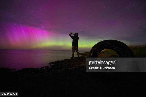 Man is taking pictures of the Aurora Australis as it illuminates the night sky above the waters of Lake Ellesmere on the outskirts of Christchurch,...