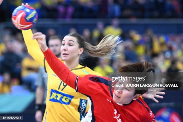 China's left back Mengxue Zhou scores a goal in front of Sweden's pivot Anna Lagerquist during the preliminary round Group A match between Sweden and...