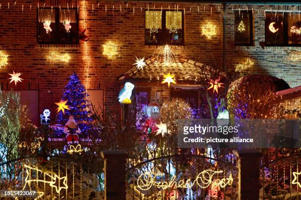 December 2023, Saxony-Anhalt, Gatersleben: The figure of Santa Claus sits in the front garden surrounded by numerous lights that illuminate the Lange...
