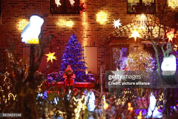 December 2023, Saxony-Anhalt, Gatersleben: The figure of Santa Claus sits in the front garden surrounded by numerous lights that illuminate the Lange...