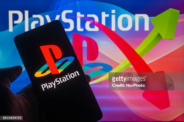 The PlayStation logo is being displayed on a smartphone with a PlayStation and a stock graph visible in the background, in this photo illustration,...
