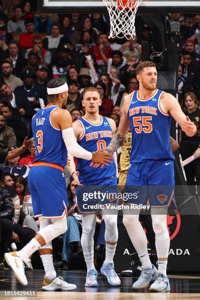 Josh Hart, Donte Divincenzo, and Isaiah Hartenstein of the New York Knicks high five during the game against the Toronto Raptors on December 1, 2023...