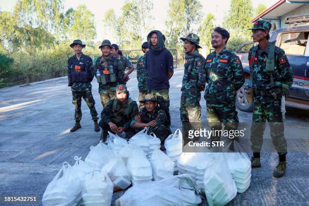 This photo taken on November 28, 2023 shows members of the Loikaw Local People's Defence Force posing in front of lunchboxes that will be sent to...