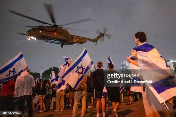 People wave flags and cheer as a second helicopter with Israeli hostages released earlier by Hamas lands at Schneider medical centre on the third day...