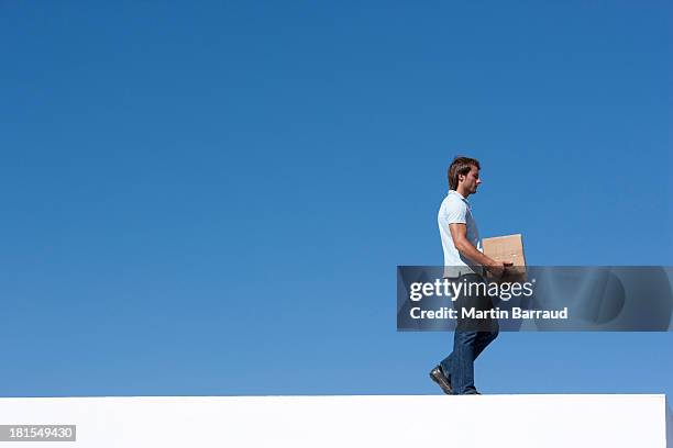 man walking with cardboard box outdoors with blue sky - skybox stockfoto's en -beelden