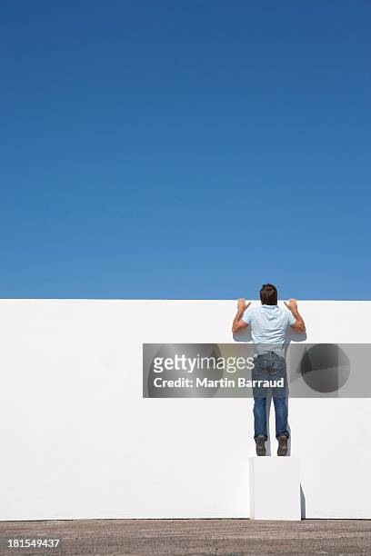 mann treiben auf der wand im freien mit blauem himmel - neugierde stock-fotos und bilder