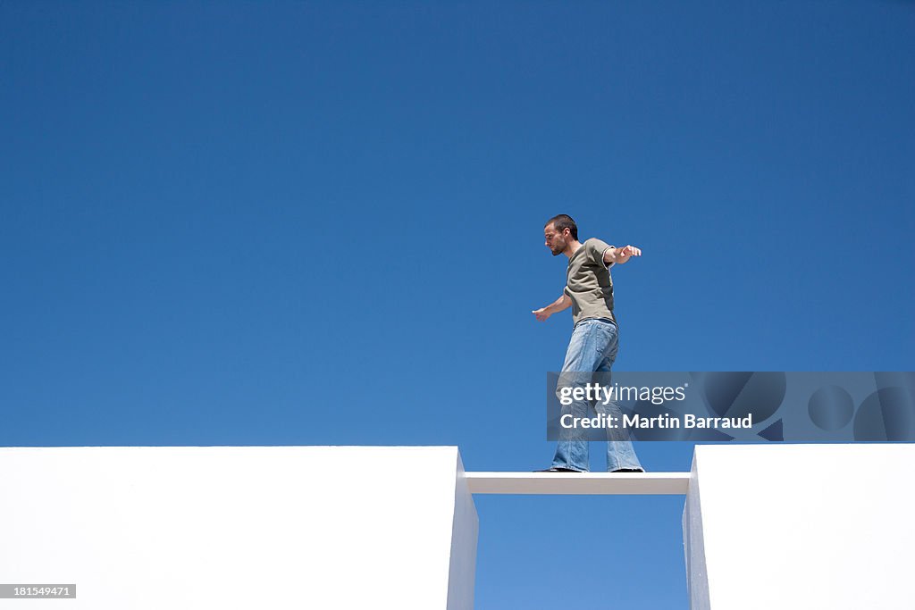 Man walking on board between two walls outdoors