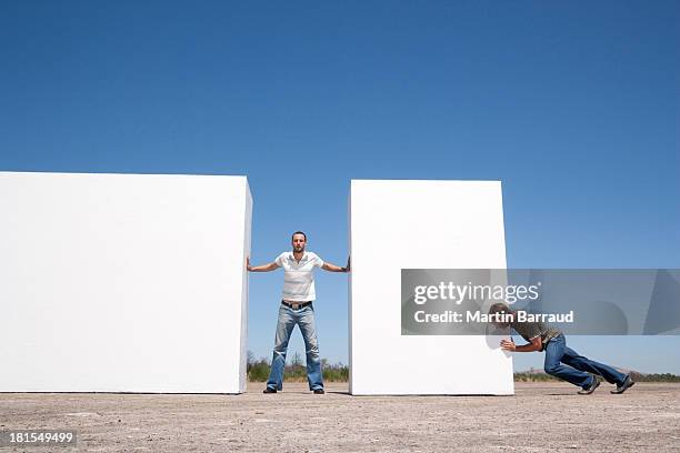 man standing between two walls pushing outdoors with adversary - man pushing stock pictures, royalty-free photos & images