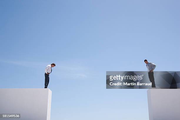 uomini d'affari in piedi guardando giù sulla parete - separation foto e immagini stock