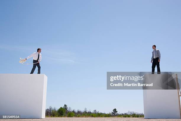 geschäftsleute auf wand werfen seil zu einem - businessman challenge stock-fotos und bilder