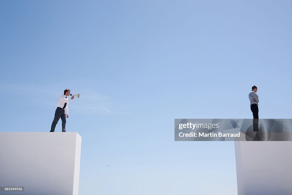 Geschäftsmann mit Megafon an der Wand schreien auf Geschäftsmann auf Wand mit gap