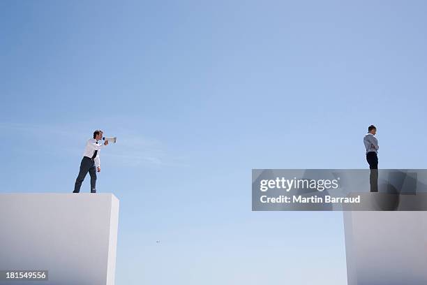 businessman with megaphone on wall shouting at businessman on wall with gap - achievement gap stock pictures, royalty-free photos & images