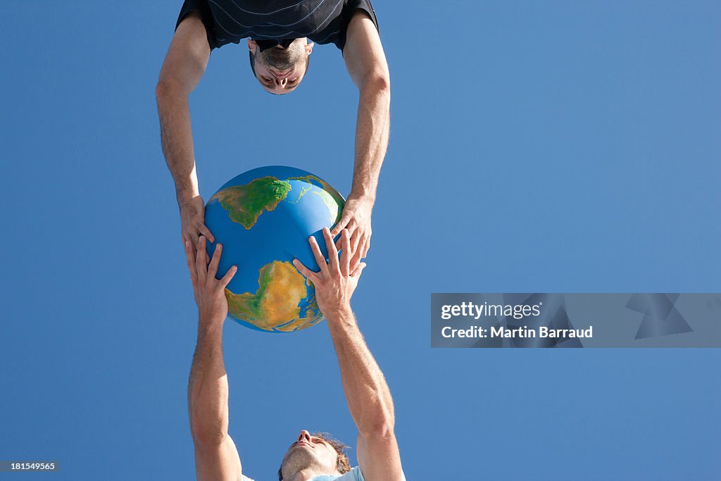 Two men passing globe outdoors