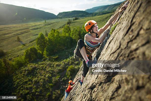 guy and a girl, rock climbing during sunset. - rock climbing stock-fotos und bilder