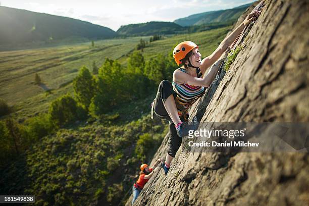 guy and a girl, rock climbing during sunset. - alpinismo fotografías e imágenes de stock